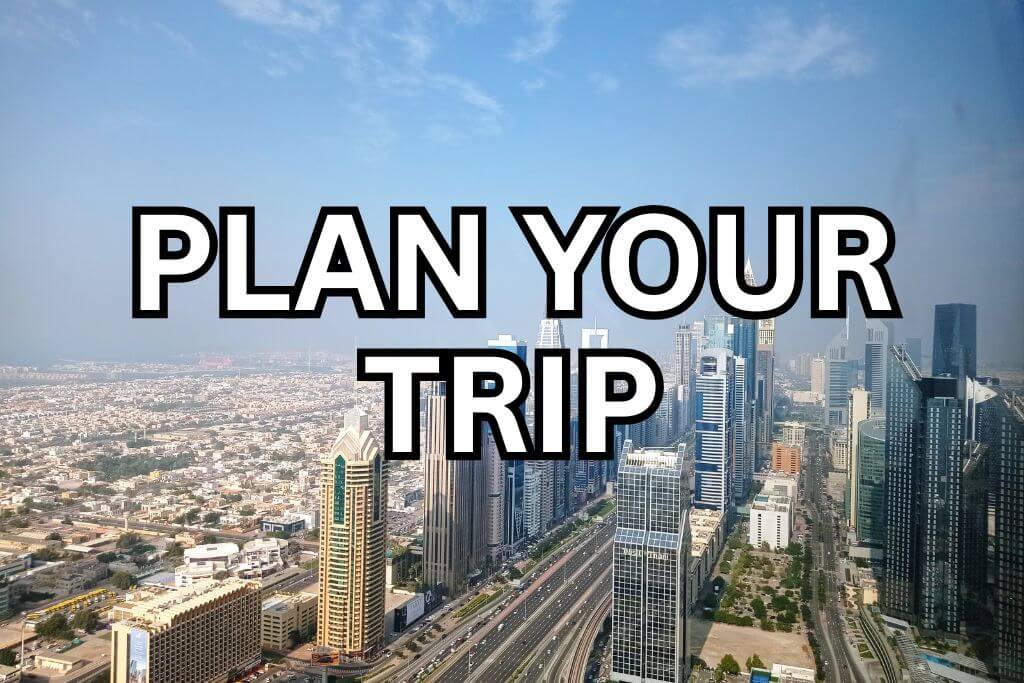 Aerial view of Dubai skyline with tall buildings and highways with text overlay 'PLAN YOUR TRIP
