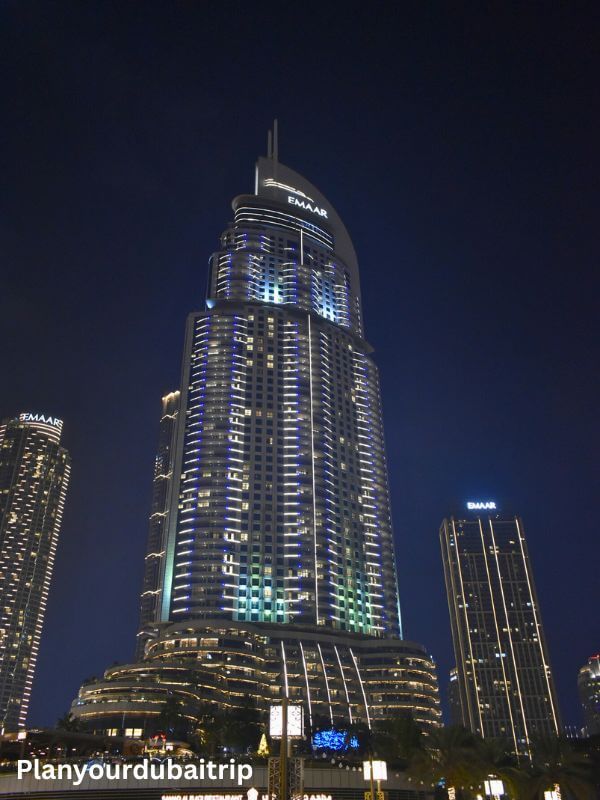 Address Downtown Hotel in Dubai lit up at night with blue and white lights on the tall tower.