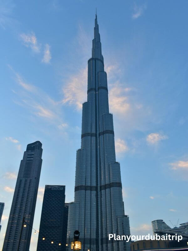 Burj Khalifa, the tallest building in the world, rising high into the blue sky in Dubai with other tall buildings nearby.
