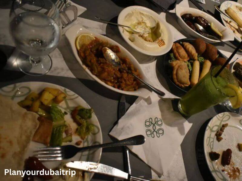 Food in Abd El Wahab Souk Al Bahar Restaurant A table full of Lebanese dishes at Abd El Wahab Restaurant in Downtown Dubai, including hummus, falafel, stuffed pastries, a stew, and a fresh green drink.