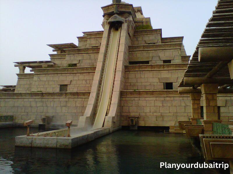 Leap of Faith water slide at Aquaventure Water Park in Dubai with a steep drop through a pyramid-shaped tower into the pool below.
