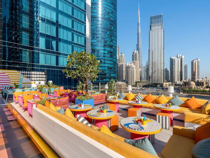 Lolita PoolBar and Lounge at Pullman Dubai Downtown hotel with colorful seating, bright cushions, and views of Burj Khalifa and the city skyline.
