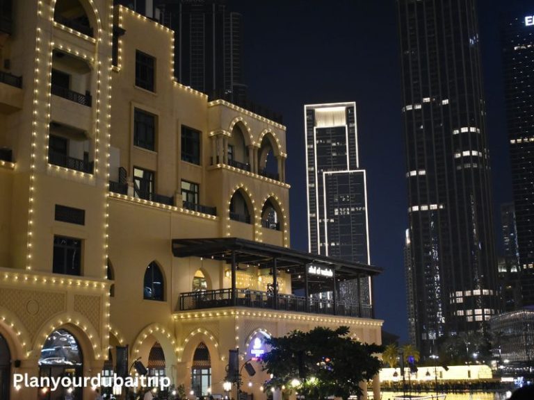 Souk Al Bahar in Dubai lit up at night with arched windows outlined in lights and tall buildings in the background.