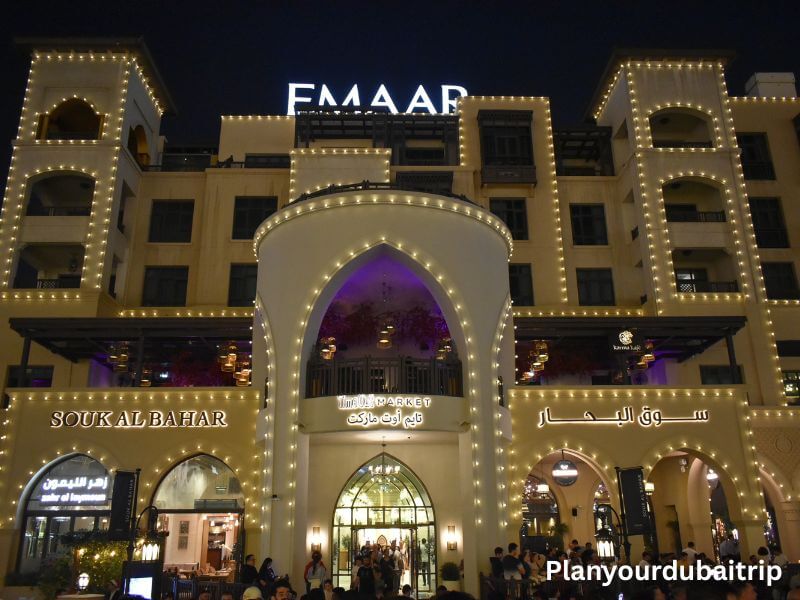 Restaurants at Souk Al Bahar in Dubai with a large lit-up archway entrance and people dining on the terrace at night.