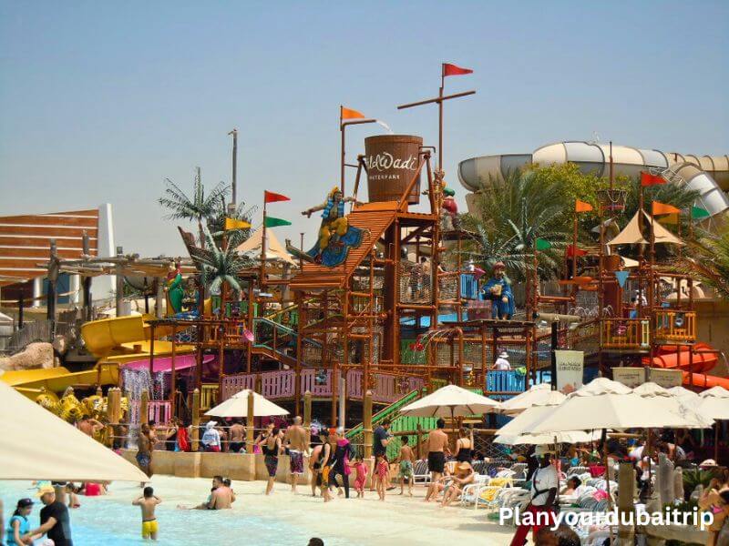 Wild Wadi Water Park in Dubai with colorful water slides, a big wooden play structure, and people enjoying the pools on a sunny day.