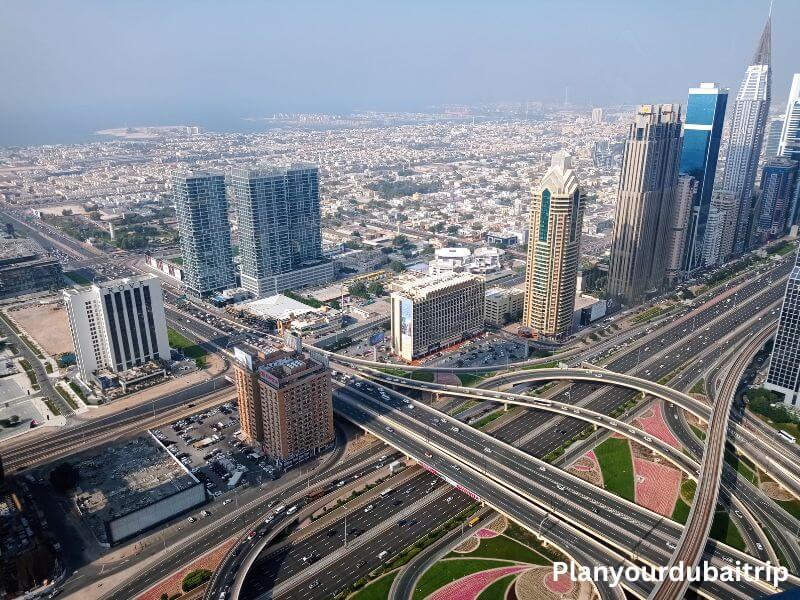 Dubai from above A top view of Dubai showing a busy highway interchange, tall buildings along Sheikh Zayed Road, and the city spreading all the way to the sea in the distance.