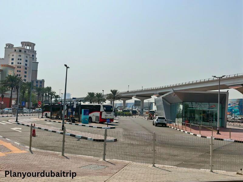 Dubai buses parked at a bus station, with the metro line running overhead.