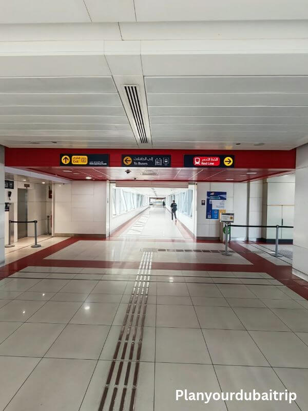 Dubai metro Walkway inside a Dubai Metro station, with signs pointing to the exit, the buses, and the Red Line.