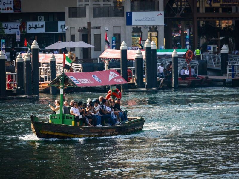 Traditional Abra in Dubai Traditional abra boat full of passengers crossing Dubai Creek, with a marine transport station behind it.